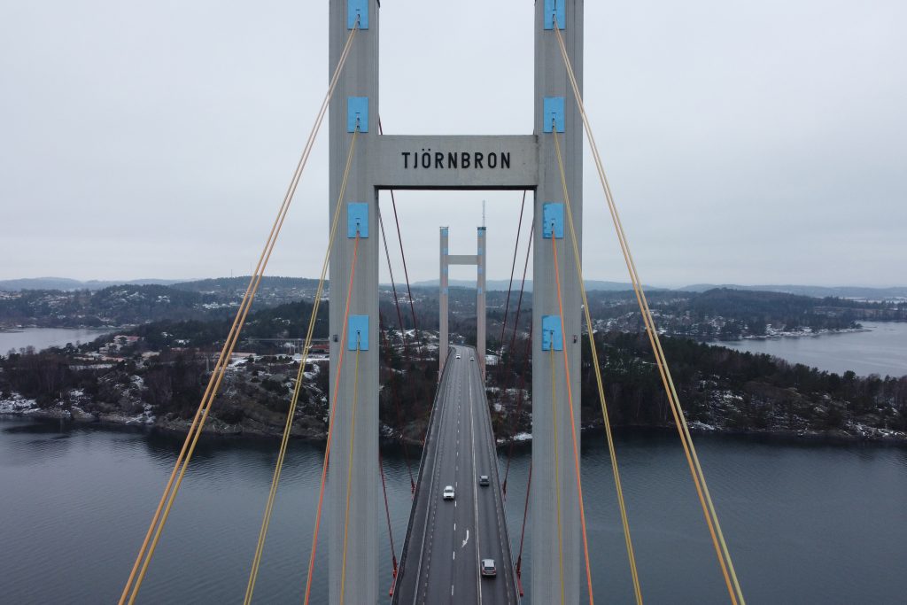 Drönarbild på Tjörnbron framifrån. Man ser skylten där det står Tjörnbron längst fram och även fem personbilar som kör på bron.