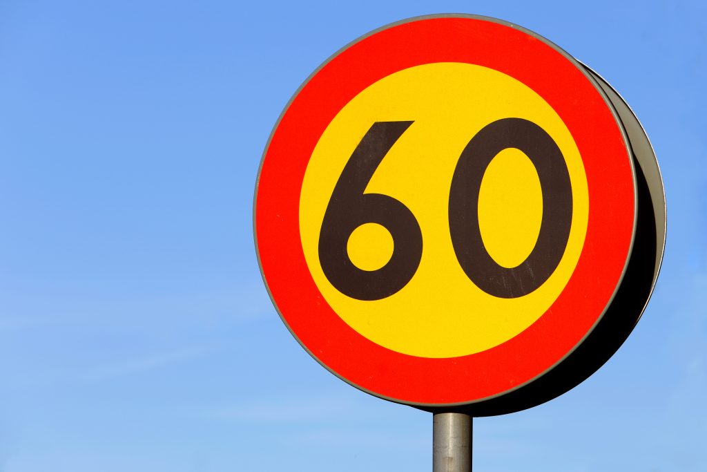 vägmärke anger att högsta tillåtna hastighet är 60 km/h, mot en blå himmel.