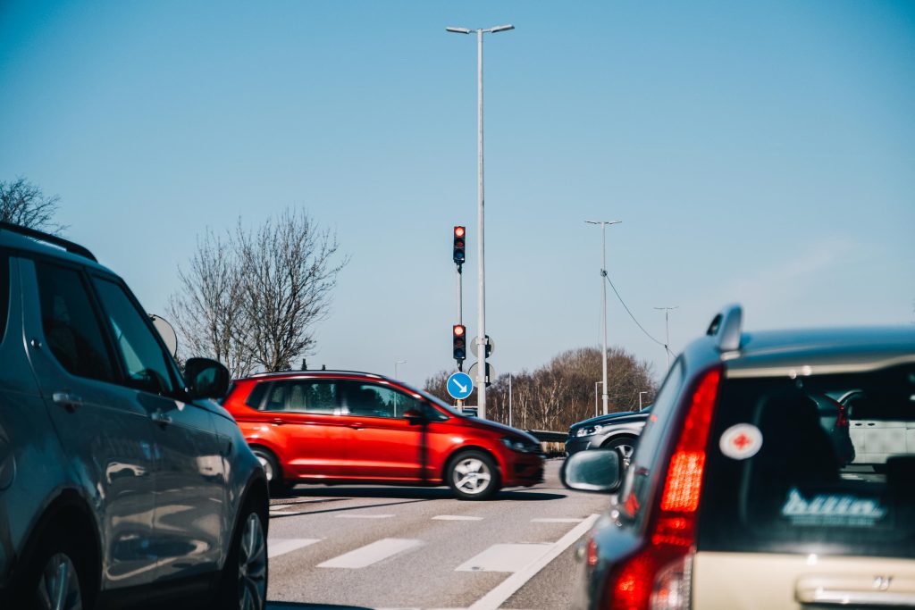 Bilar syns köra i en korsning med trafiksignaler.