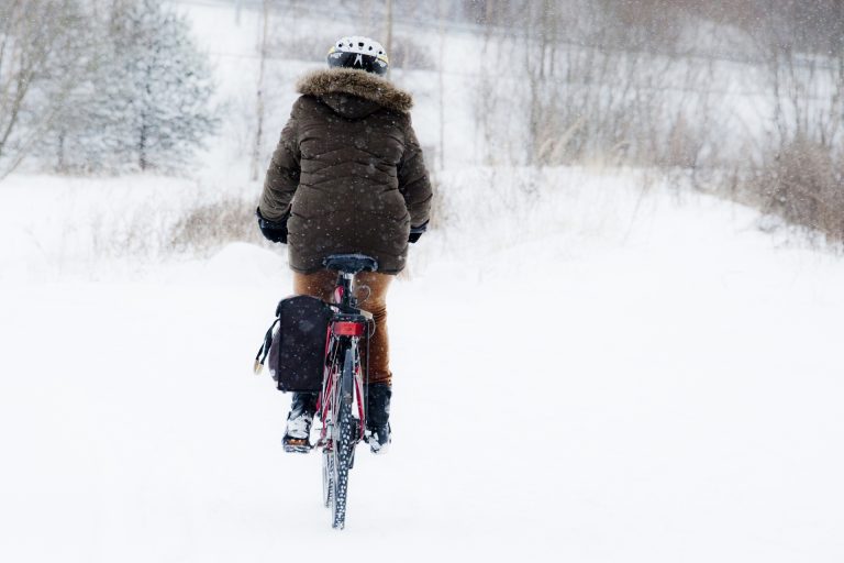 Ryggen på en cyklist som kör genom ett snöigt landskap