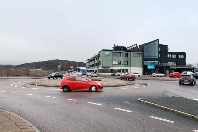 Rondellen vid korsningen Backavägen - Södra Deltavägen en röd bil kör just in i rondellen.