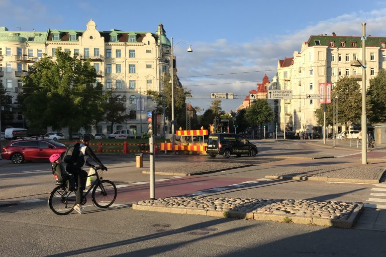 Bilar, cyklister och gående syns vid Burgårdsplatsen vid Scandinavium.